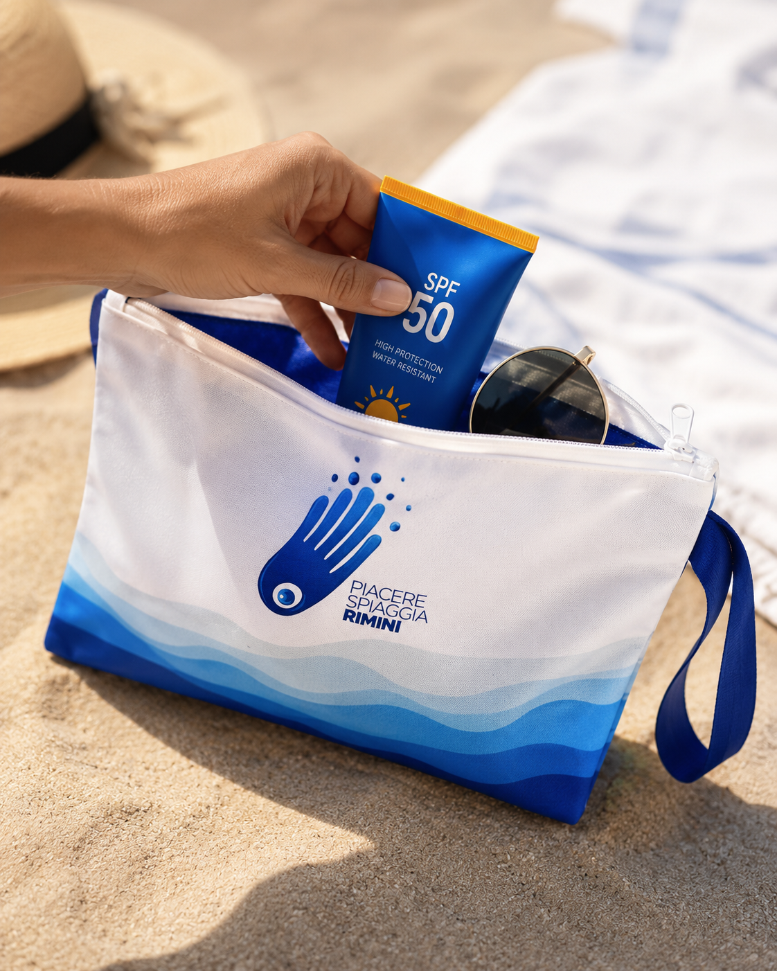 Pochette da spiaggia impermeabile Piacere Spiaggia Rimini, bianca con dettagli blu, ideale per smartphone e accessori da mare.