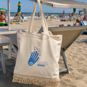 Borsa mare con frange Piacere Spiaggia Rimini appesa a un lettino sulla spiaggia