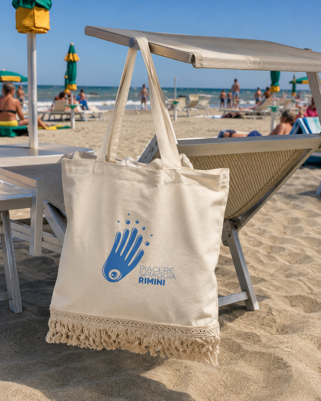 Borsa mare con frange Piacere Spiaggia Rimini appesa a un lettino sulla spiaggia